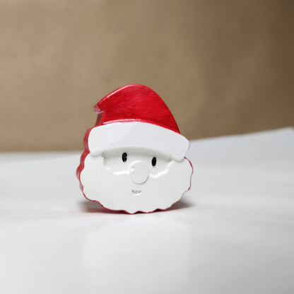 santa made with cement hand painted with red, white and black acrylic paint, photographed on a table top.