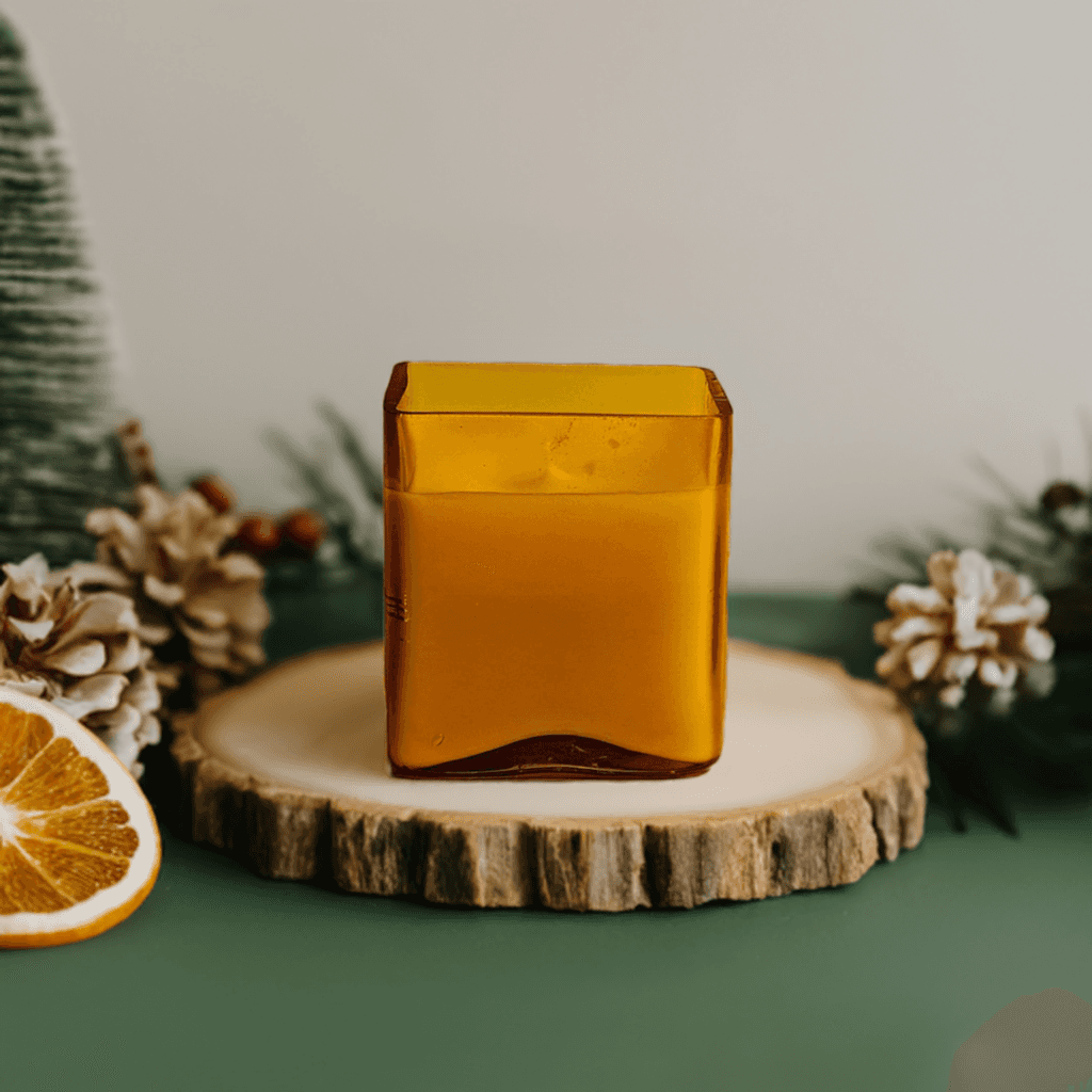 Amber glass candle on wood slice, holiday pinecones and decor.