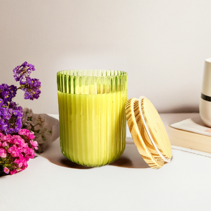 Green ribbed U-shaped glass jar candle with wooden lid.