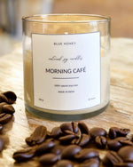 Blue Honey Morning Café natural soy wax candle in a clear glass jar with coffee beans.