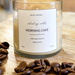Blue Honey Morning Café natural soy wax candle in a clear glass jar with coffee beans.