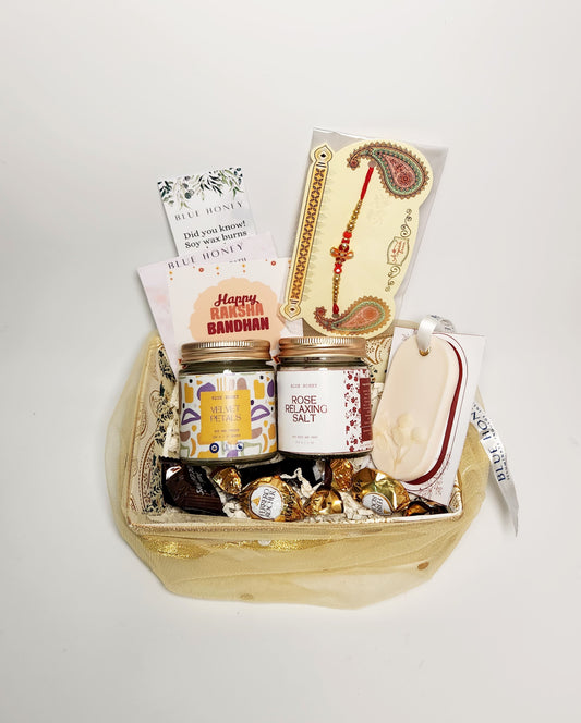 Gift basket with candle and bath salt jars, candies, and decorative items on a white background