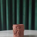 Jesmonite candle jar with a design on a marble table against a green curtain background