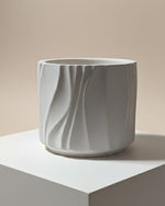 Modern Wave Vessel scented Jesmonite candle in a light grey, textured finish, displayed from the front.