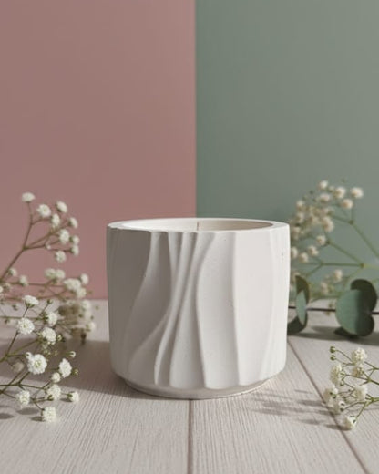 White textured candle jar on a wooden surface with a minimalistic background