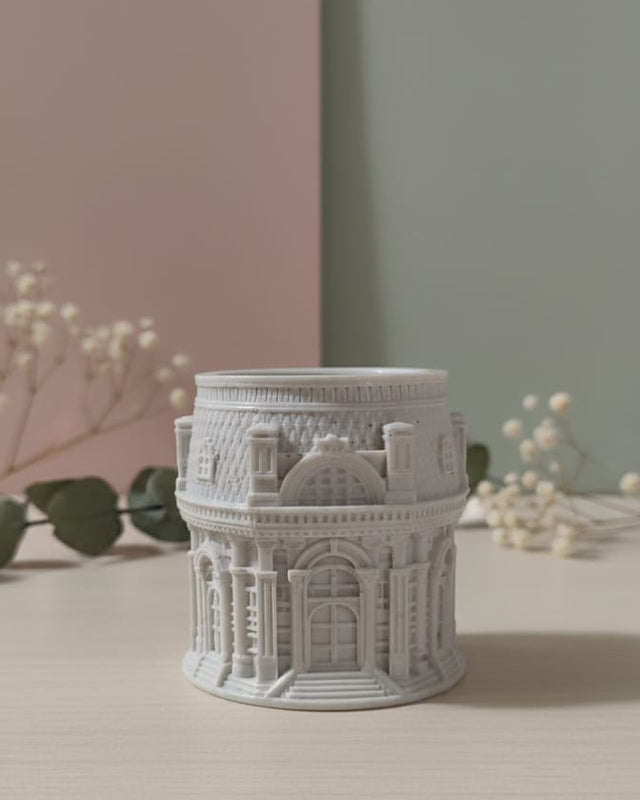 The Grand Pavilion Architectural Jesmonite Candle Jar, a detailed grey miniature building, displayed on a table.