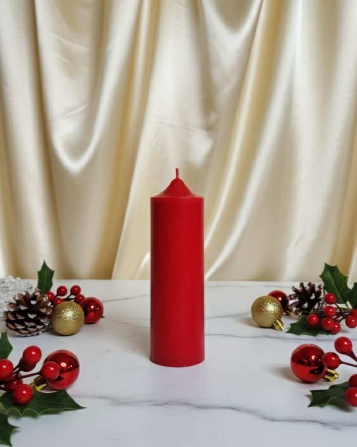 Red candle on a marble surface with decorative elements against a beige curtain background