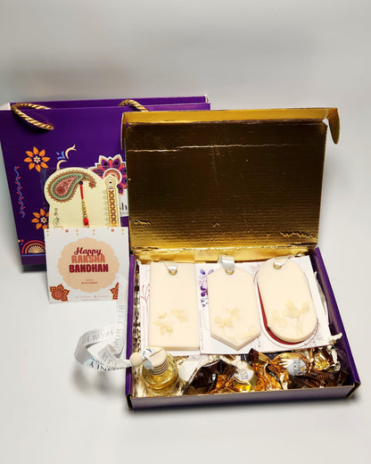 Gift set with wax sachet and car diffuser and snacks in a decorative box on a white background