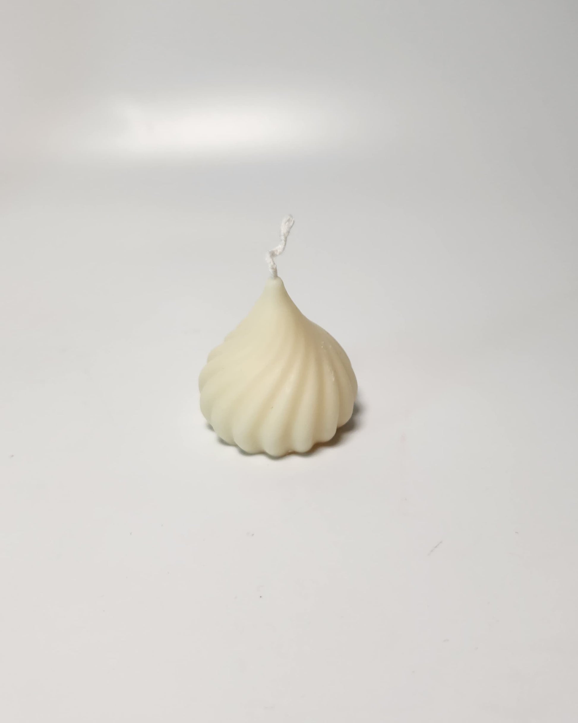 White modak candle with a textured design on a light gray background