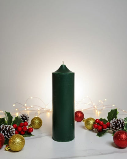 Green candle with Christmas decorations on a white background