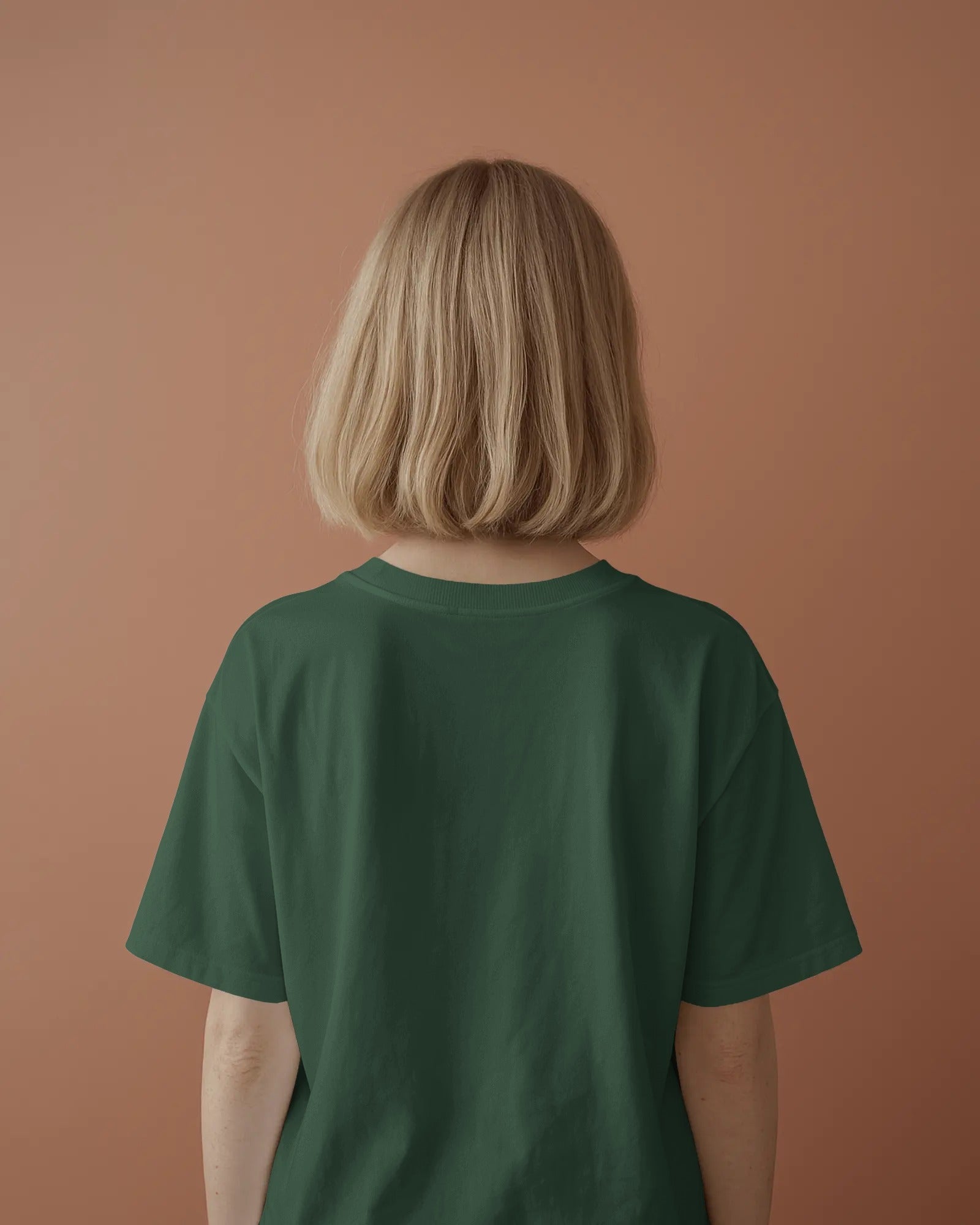 plain back view of a female standing wearing an oversized Bottle Green Anthophile tshirt
