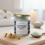 Jar of Blue Honey Chamomile Relaxing Salt for body and feet, displayed with dried chamomile flowers and a wooden spoon.