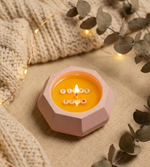 Close-up front view of a "I Love You" soy wax candle in a baby pink concrete jar with a lit flame.