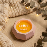 Close-up front view of a "I Love You" soy wax candle in a baby pink concrete jar with a lit flame.