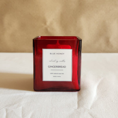 Front view of a red glass jar candle labeled 'Gingerbread' from the Christmas Candle Collection.