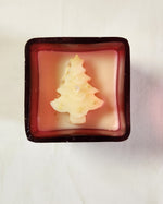 Top view of a Christmas tree-shaped candle with gold glitter in a red glass jar, perfect for holiday gifting.