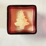 Top view of a Christmas tree-shaped candle with gold glitter in a red glass jar, perfect for holiday gifting.