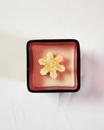 Square red and white candle topped with a gold snowflake, part of the Christmas Candle Collection.