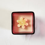 Square red and white candle topped with a gold snowflake, part of the Christmas Candle Collection.