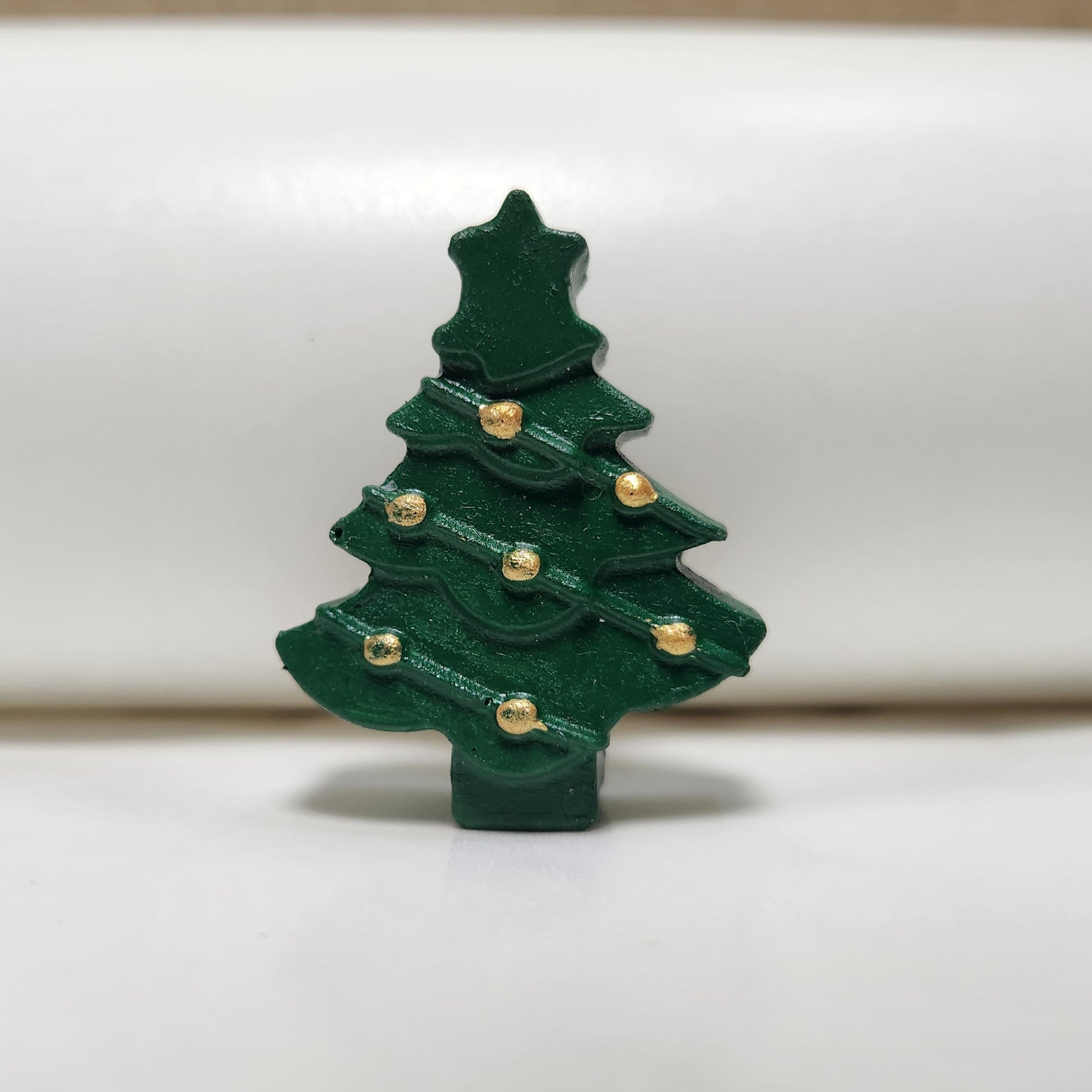 christmas tree cement art hand painted with green and gold acrylic paint, photographed on a table top