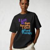Black unisex crew neck t-shirt with 'I lift in Gym Because I Can't Afford Therapy' graphic print.