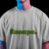 White unisex oversized t-shirt featuring "Escape" in green maze-like typography on the front.