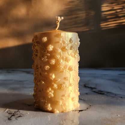 gold dust flower pillar soy wax candle on a table top