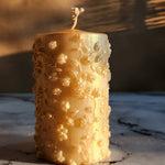 A 4-inch tall gold dust soy wax pillar candle with embossed floral details.