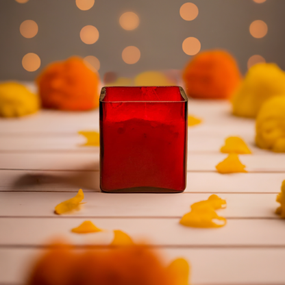 Red glass jar candle amidst yellow decorations