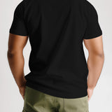 Back view of a black Wildfire 'Pushpa 2' t-shirt worn by a person with green cargo pants.