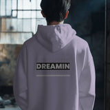 Back view of a Dreamin oversized unisex hoodie in a light purple color with graphic text.