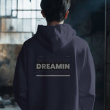 Back view of a black Dreamin oversized unisex hoodie with graphic text, styled for streetwear.