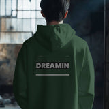Back view of a unisex oversized dark green hoodie with 'Dreamin' graphic print.