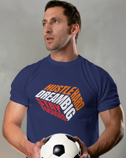 A male model standing with a football in his hands wearing 'Hustle Hard' tshirt in Navy Blue color