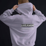 Back view of a person wearing a light purple Dreamin oversized unisex hoodie with graphic text.