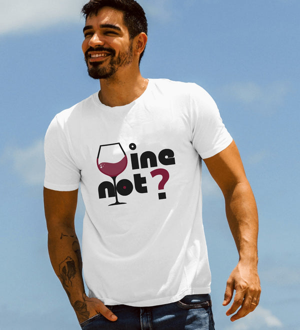 A man wearing a white "Wine Not?" graphic t-shirt, smiling outdoors against a blue sky.