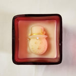 Top view of a red glass jar candle featuring a white snowman with a gold hat and glitter details.