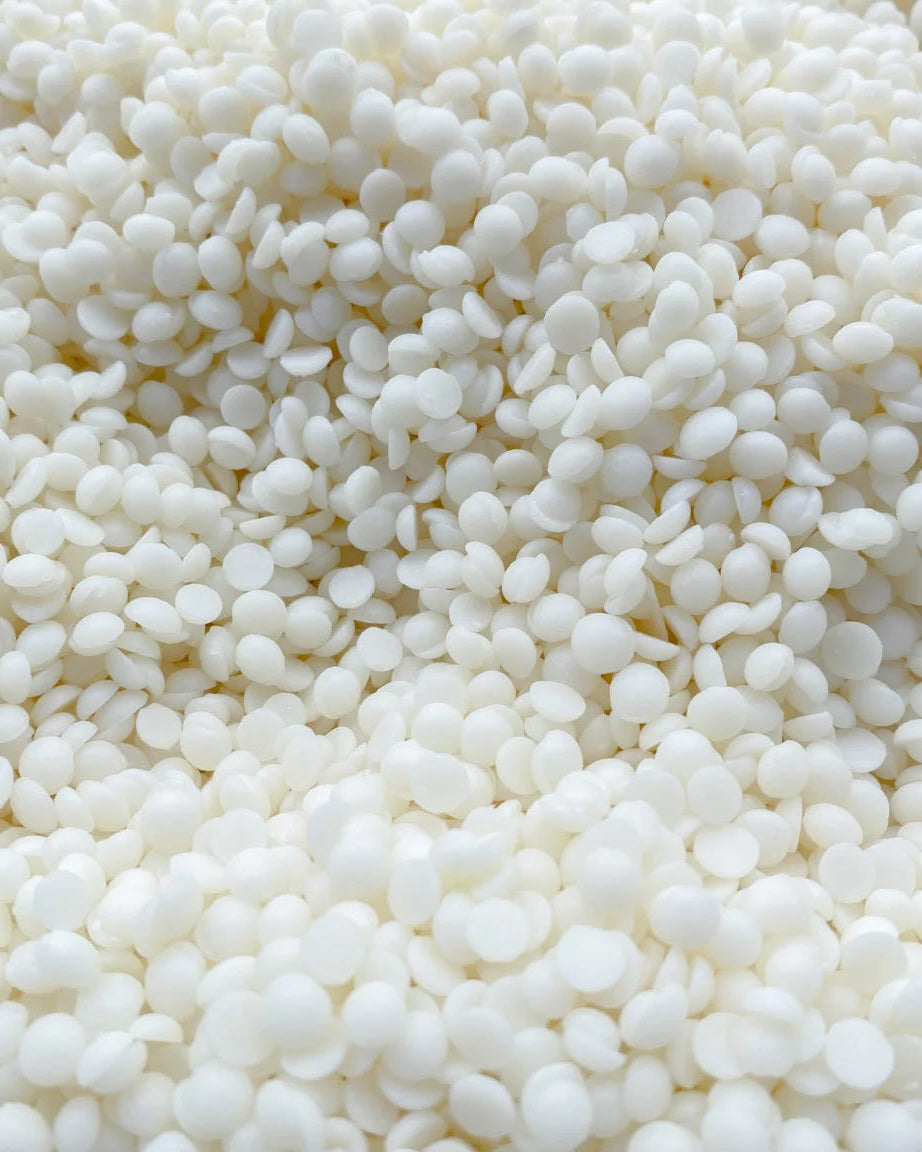 Close-up view of white soy wax pellets, ideal for making container candles, shown in a detailed shot.