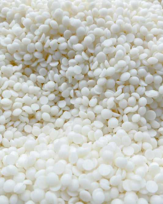 Close-up view of white soy wax pellets, ideal for making container candles, shown in a detailed shot.