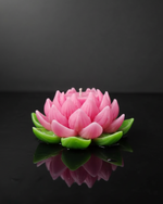 The Purity Lotus Candle in pink and green, a handmade floating candle with detailed petals, shown from the front.