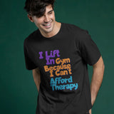 Black unisex crew t-shirt with 'I Lift In Gym Because I Can't Afford Therapy' graphic print on the front.