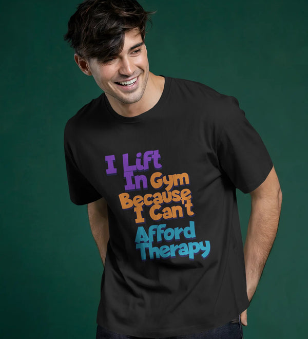 Black unisex crew t-shirt with 'I Lift In Gym Because I Can't Afford Therapy' graphic print on the front.