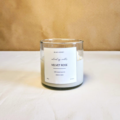 daisy flower candle inside a clear jar on a table top. label reads Velvet Rose