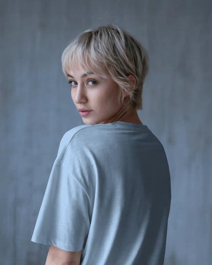 an Asian female model with blone hair showing the back of the baby blue Selenophile oversized tshirt
